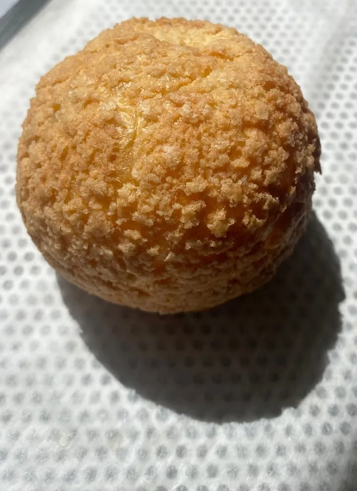 Chou craquelin à la fleur d'oranger, gros plan sur la pâte dorée, sur papier cuisson.